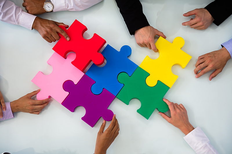 Group Of Businesspeople Solving Jigsaw Puzzle